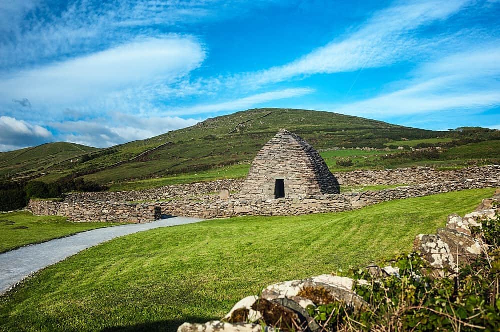 The dry stone Gallarus Oratory in a green field on the Dingle Peninsula